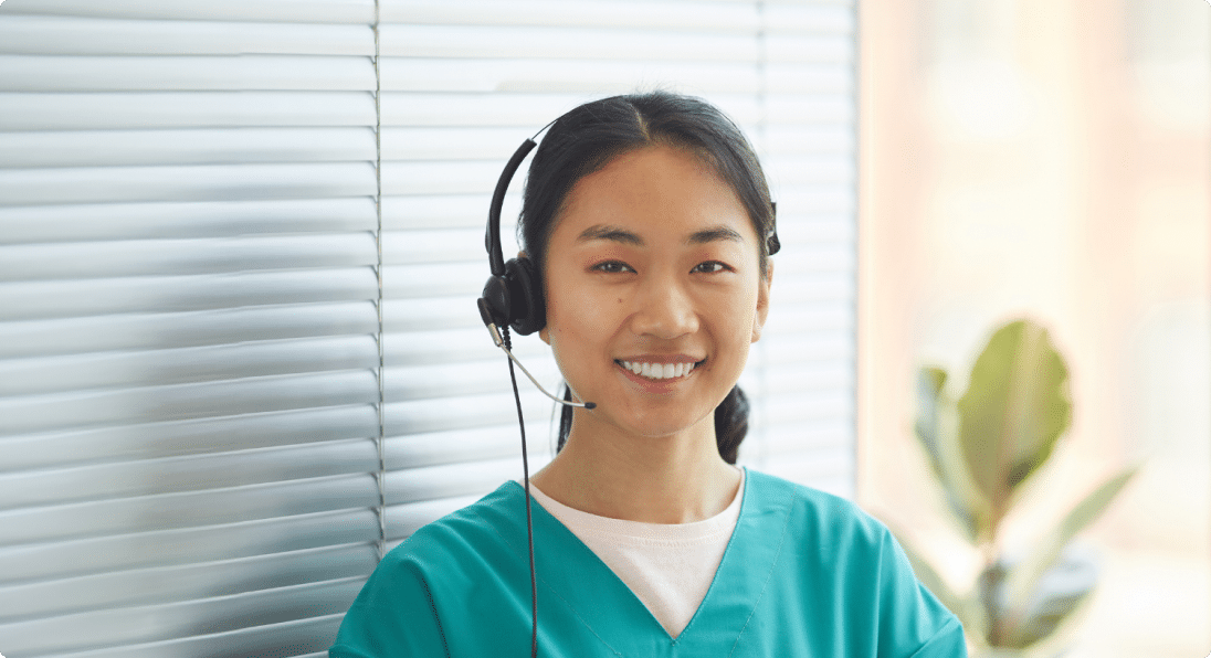 Nurse wears a headset sitting in a call center answering patient calls.