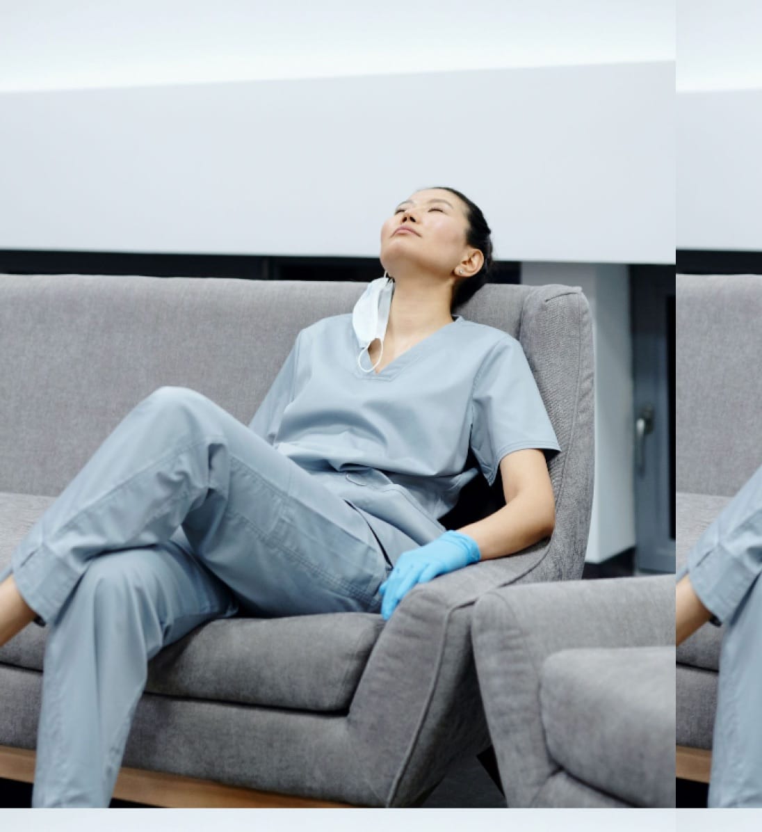 Nurse sitting cross legged on a couch, with head leaned back and eyes closed.