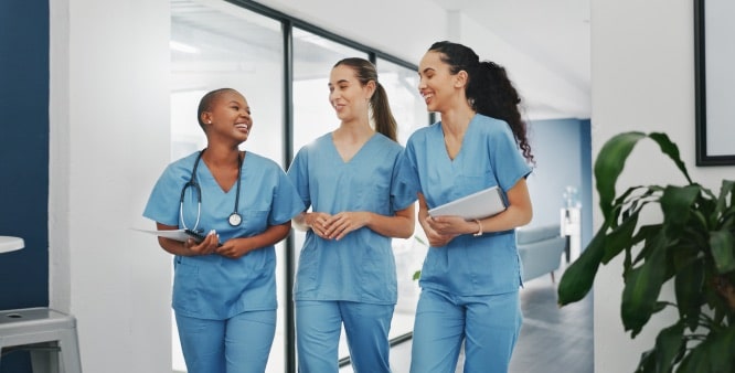 Three medical providers walking down a hallway smiling and laughing.