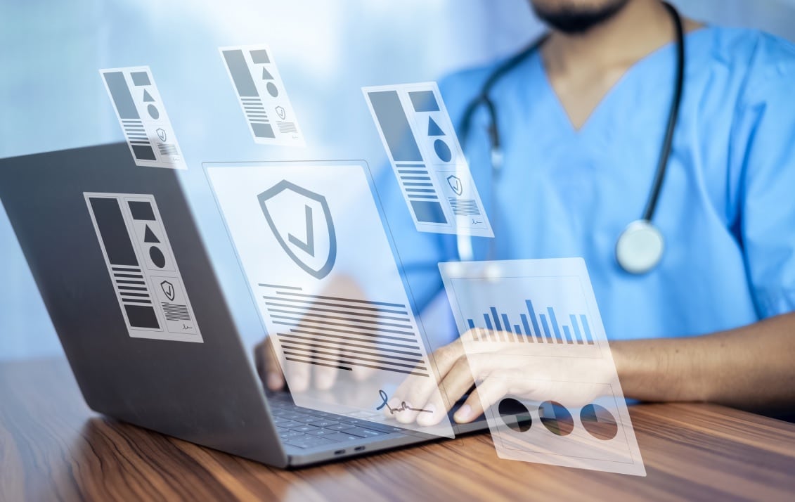 Medical provider types on a laptop with a holographic image of various file types hovers above it.