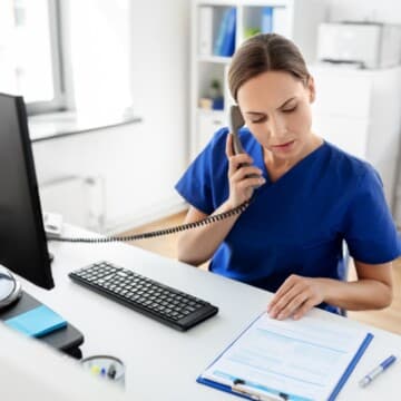 no-1-mistake Healthcare professional talking on the phone, leaning over to read patient chart on clipboard.