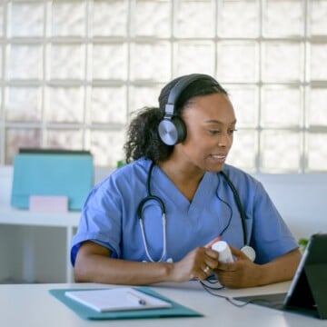 virtual care Nurse wearing a headset with a medicine bottle in hand, while virtually talking with a patient.